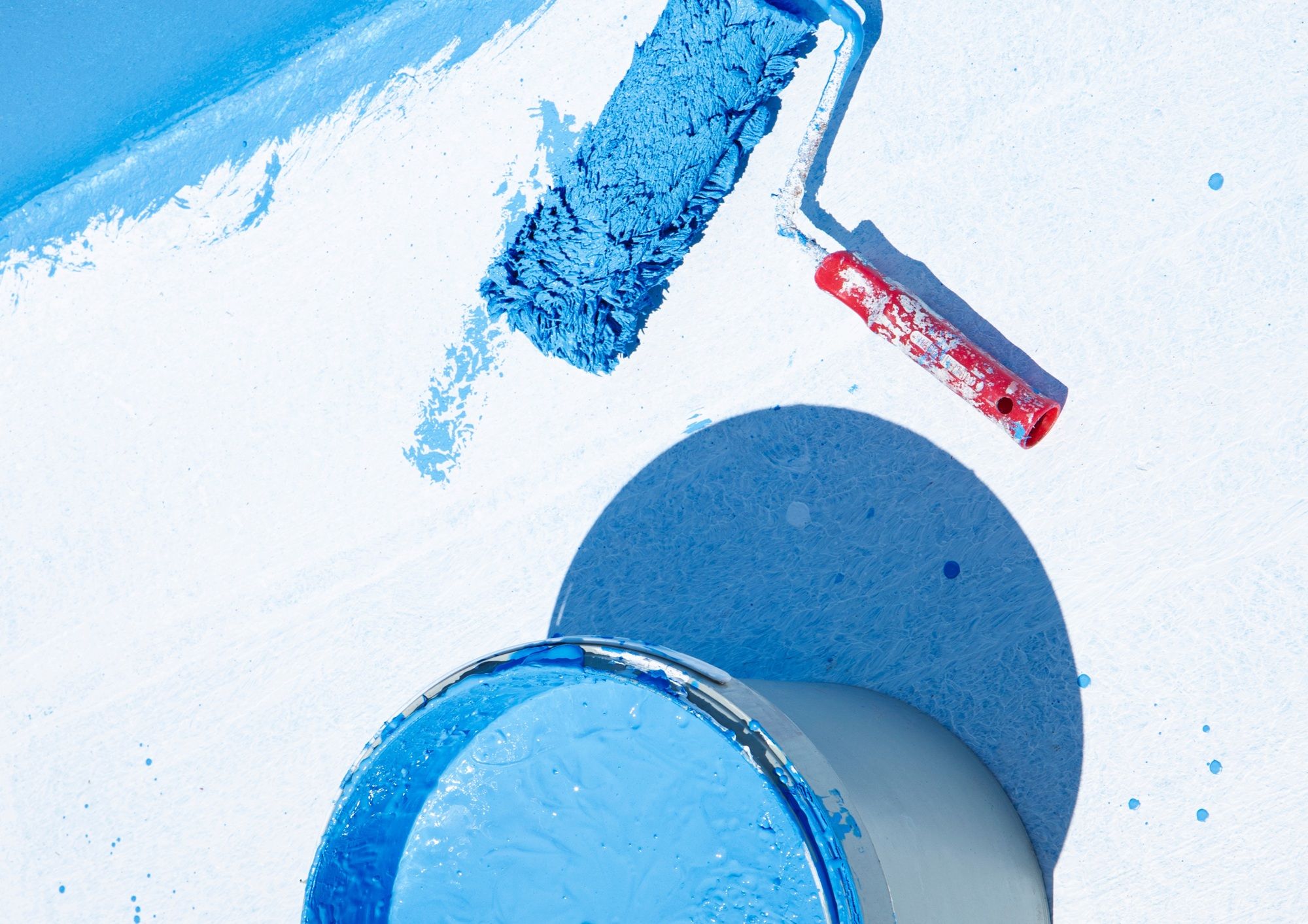 Wałek malarski pokryty niebieską farbą – przygotowanie do malowania