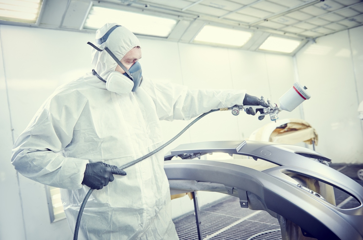 Aplikacja lakieru samochodowego przez specjalistę w kabinie lakierniczej &ndash; praca z rozcieńczalnikami